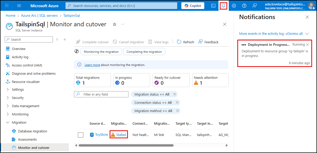 The stalled migration status is highlighted. The Azure notification icon is highlighted in the top bar, and the deployment in progress message is displayed.